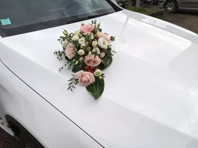 Décoration florale de voiture de mariée classique avec des roses rose et lisianthus blancs, et des baies rouges.