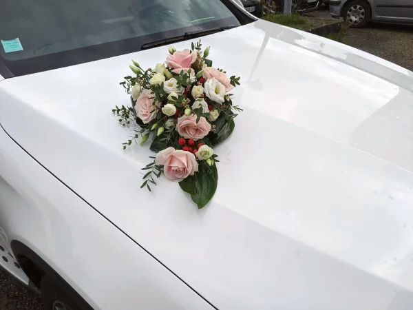 Décoration florale de voiture de mariée classique avec des roses rose et lisianthus blancs, et des baies rouges.