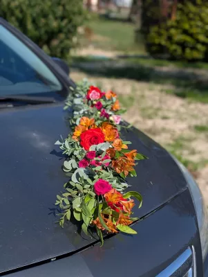Décoration florale de voiture de mariage style bohème, avec roses rouges, alstroemeria orange et eucalyptus.