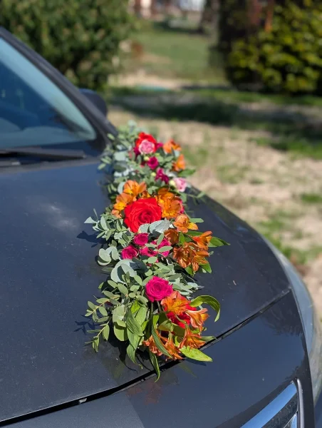 Décoration florale de voiture de mariage style bohème, avec roses rouges, alstroemeria orange et eucalyptus.