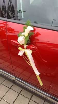 Décoration florale de poignée de voiture style classique avec une rose crème, un arum blanc et du feuillage vert.