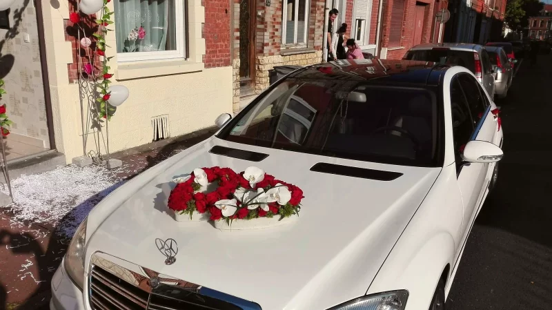 Classic wedding car decor with red roses, white orchids, and green foliage for an elegant autumn wedding.