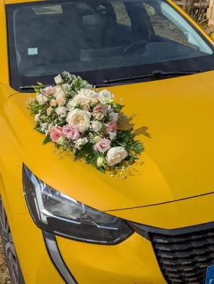 Composition florale pour véhicule de mariés, avec roses blanches, roses pâles et gypsophile, pour un mariage champêtre.