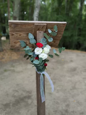 Décoration florale champêtre pour allée de cérémonie avec roses blanches, fleur rouge pompon et feuilles d'eucalyptus.