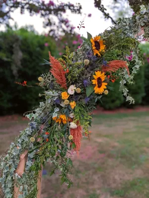 Gros plan sur la décoration de l'arche florale champêtre avec tournesols, chardons et lierre.