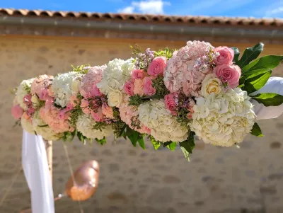 Détail de l'arche florale de mariage avec hortensias blancs et roses, roses claires et feuillage.