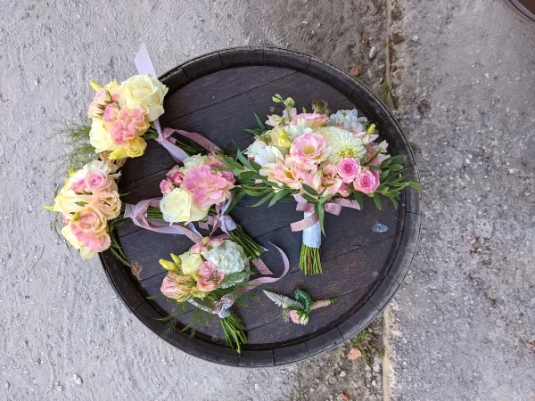 Ensemble floral champêtre pour mariage avec bouquet de mariée, bouquets de demoiselles et boutonnière, aux teintes de blanc, rose et vert.