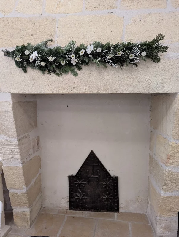 Guirlande de cheminée classique avec sapin, fleurs blanches et accents givrés pour une décoration de mariage hivernal.