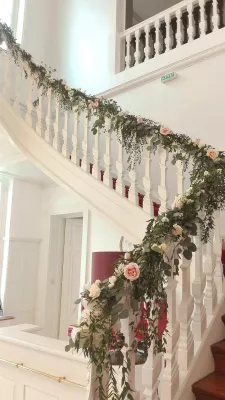 Floral garland for a country wedding, adorning a staircase, with white roses, pale roses and eucalyptus foliage. An elegant decoration.