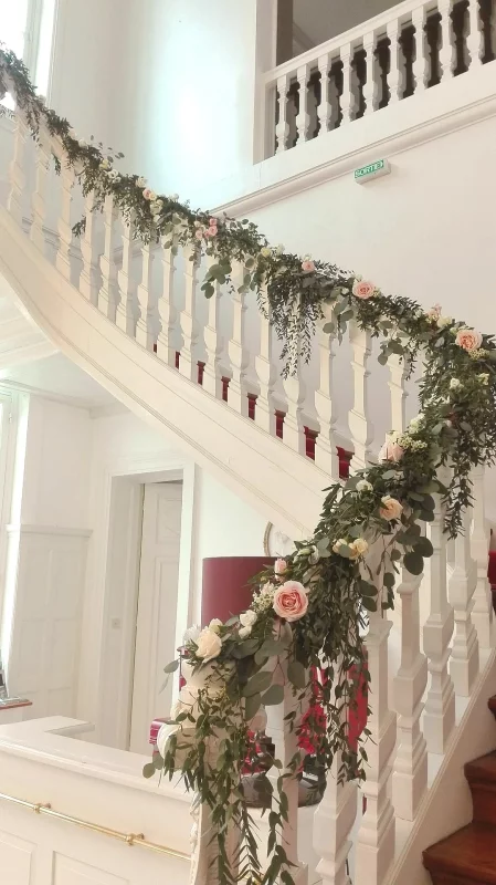 Floral garland for a country wedding, adorning a staircase, with white roses, pale roses and eucalyptus foliage. An elegant decoration.