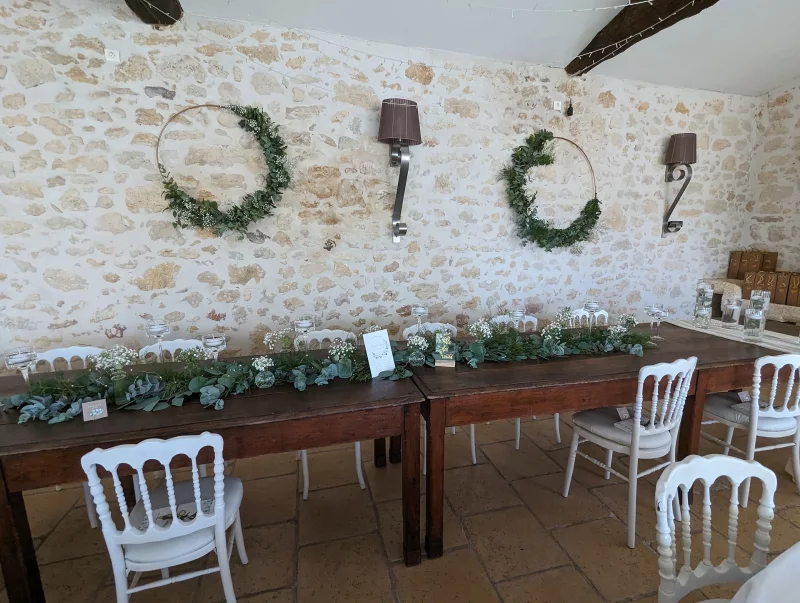 Guirlande florale champêtre en eucalyptus et gypsophile, décorant une longue table de mariage en bois.
