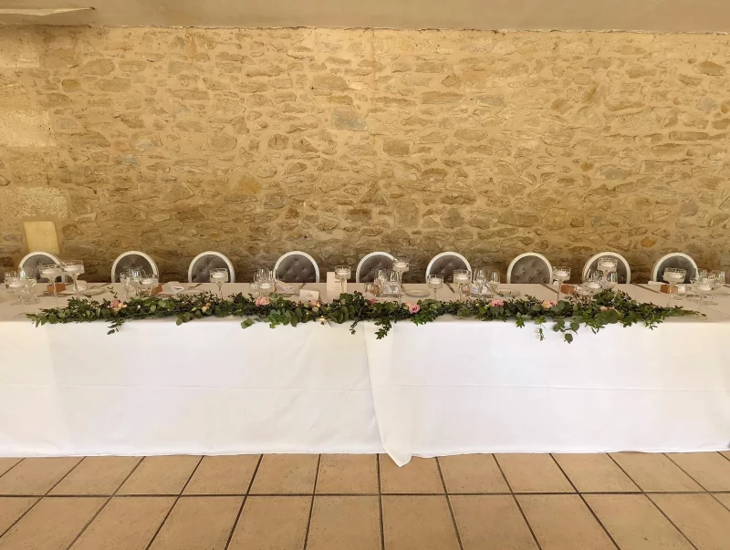 Guirlande florale champêtre pour table d'honneur avec eucalyptus et mini-roses pâles, au mariage du Domaine de Valmont.