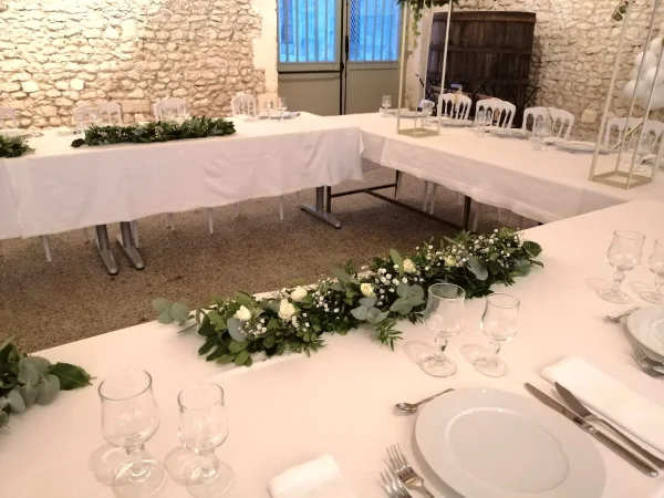 Magnifique guirlande de table de mariage champêtre, composée de roses blanches, d'eucalyptus frais et de gypsophile, créant un chemin de verdure et de fleurs.
