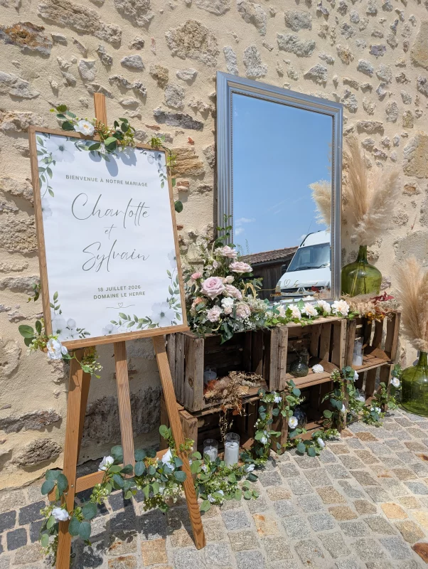 Floral welcome sign with eucalyptus and roses, sophisticated country-style decor for a wedding.