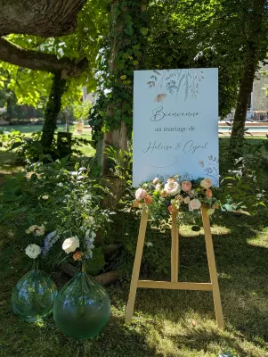 Panneau de bienvenue mariage Héloïse Cyril, décoré roses blanches, delphinium et feuillage verdoyant.