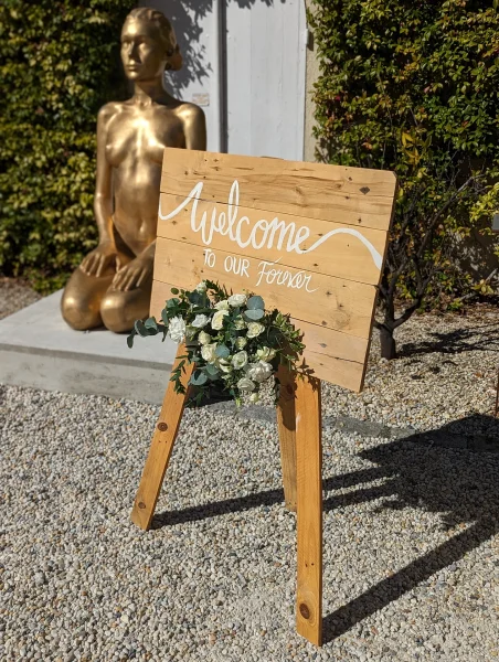 Panneau de bienvenue en bois décoré de roses blanches, gypsophile et eucalyptus pour un mariage à Pessac.