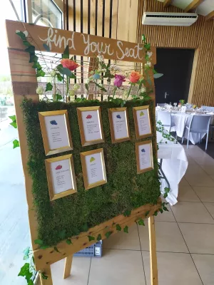 Panneau de bienvenue 'Find Your Seat' champêtre avec roses, mousse et lierre pour un mariage.