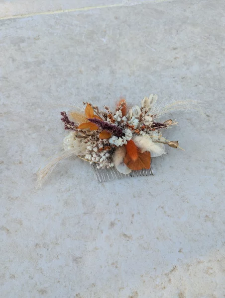 Bridal comb with dried flowers in shades of orange, terracotta, and burgundy for a rustic wedding.