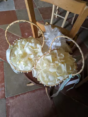 Paniers remplis de pétales de roses blanches et crème prêts à être lancés lors d'un mariage.