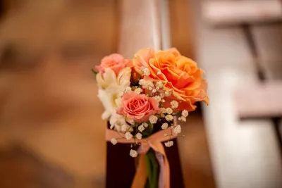 A romantic posy with peach roses, pink roses, and gypsophila, tied with a ribbon.