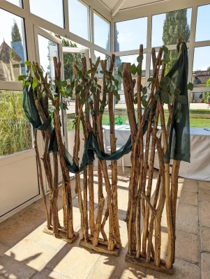 Scénographie photobooth bohème avec structure en bois brut et feuillage d'eucalyptus pour un mariage.