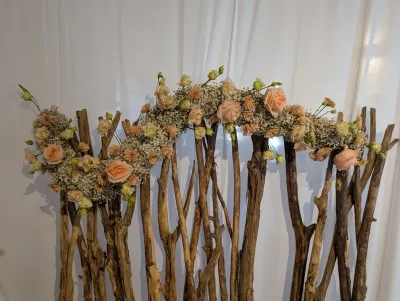 Coin photo bohème champêtre avec arche florale de roses pêche, gypsophile et branches de bois pour mariage.