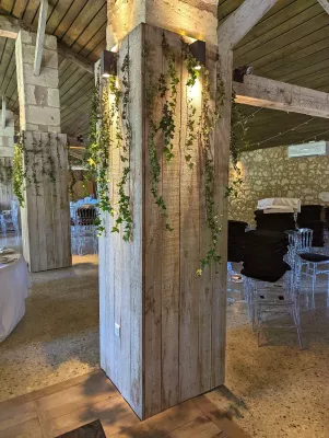 Piliers en bois décorés de lierre grimpant vert pour une ambiance naturelle et champêtre à l'intérieur de la salle de réception.