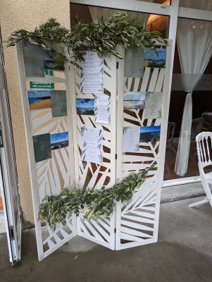 Végétalisation de plan de table champêtre avec guirlandes d'eucalyptus et branches d'olivier sur support en bois.