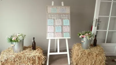 Plan de table de mariage champêtre, avec marguerites, roses pâles, gypsophile et feuillage vert dans des seaux galvanisés.