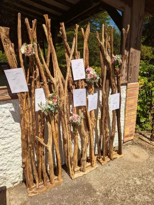 Plan de table de mariage champêtre avec bouquets de roses, gypsophile et eucalyptus sur structure en bois flotté.