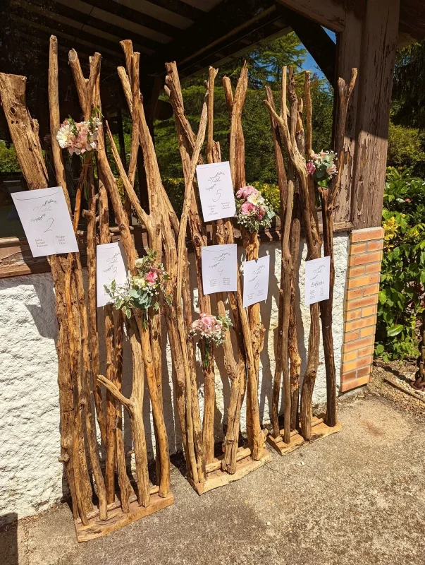 Rustic-chic Wedding Table Plan, adorned with bouquets of roses, gypsophila and eucalyptus on a driftwood structure.
