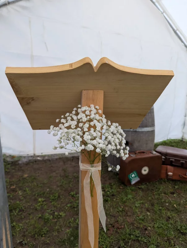 Pupitre de cérémonie en bois simple, orné d'un bouquet aérien de gypsophile blanc, pour une touche de pureté.