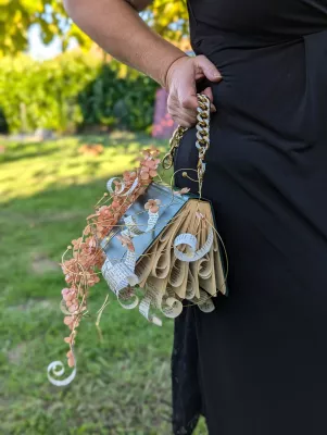 Sac original de mariée, en forme de livre, fleurs séchées couleur pêche et feuillage pour un mariage bohème.