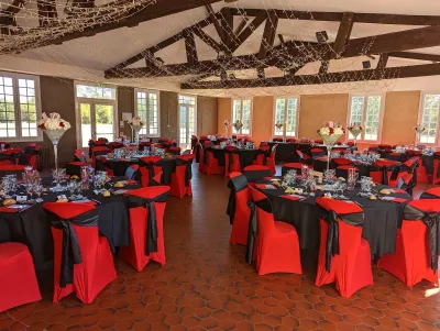 Vue d'ensemble d'une salle de réception élégante, décorée de centres de table floraux classiques avec hortensias et roses rouges.