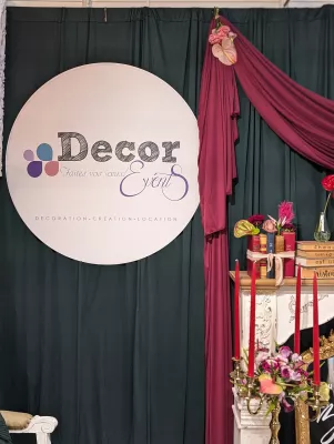 Scénographie d'événement avec logo 'Decor Events', drapés sombres et chandelier avec chandelles rouges, ambiance classique.