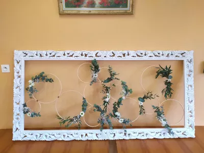 Scénographie florale murale champêtre avec cercles décorés d'eucalyptus, roses blanches et gypsophile, créant une ambiance naturelle.