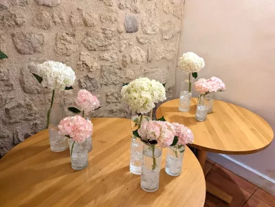 Scénographie champêtre pour mariage avec bouquets d'hortensias blancs et roses dans des vases en verre.