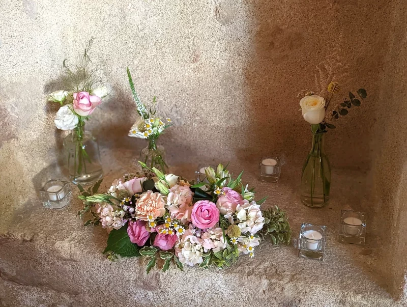 Scénographie bohème pour mariage avec roses, hortensias et marguerites, complétée par des bougies tamisées.