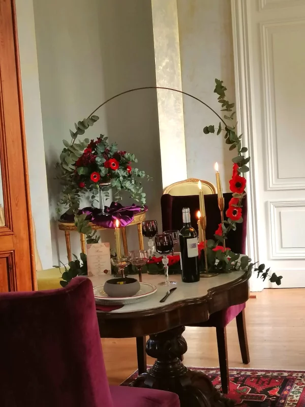Wedding head table featuring a romantic floral arrangement of eucalyptus, anemones, and red roses in Bordeaux.