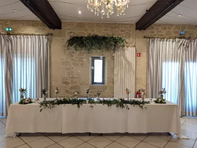 Table d'honneur végétalisée avec guirlande d'eucalyptus et ruscus, agrémentée de petites compositions florales.