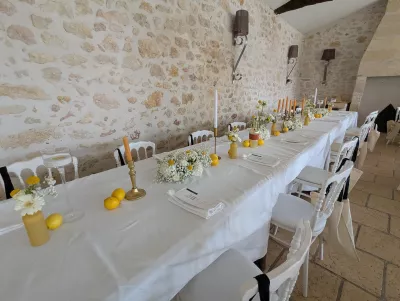 Longue table d'honneur de mariage décorée de gerberas blancs, craspedias jaunes et citrons pour un look champêtre