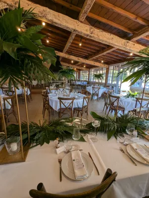 Décoration de table d'honneur avec centres de table hauts et une guirlande de feuillage tropical pour un mariage exotique.