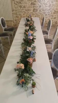 Décoration de table d'honneur champêtre avec guirlande d'eucalyptus, roses pêche, œillets et succulentes.