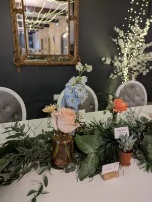 Décoration de table d'honneur champêtre avec guirlande d'eucalyptus, roses pêche, œillets et succulentes.