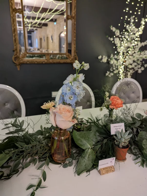 Décoration de table d'honneur champêtre avec guirlande d'eucalyptus, roses pêche, œillets et succulentes.