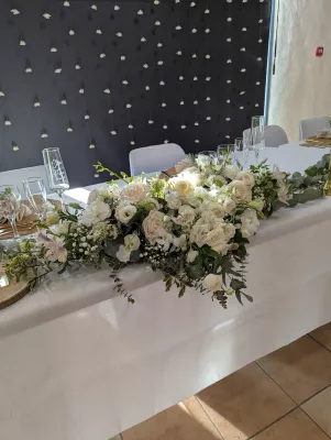 Sophisticated country-style head table floral decoration with roses and eucalyptus for a wedding.