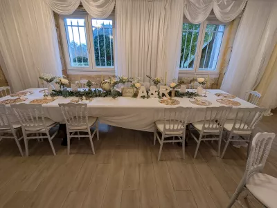 Décoration de la table d'honneur d'un mariage classique avec une guirlande florale, roses crème, gypsophile et bougies, à Capian.
