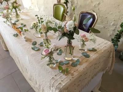 Décoration de table d'honneur champêtre avec roses, eustoma, astilbe et gypsophile dans de petits vases variés.