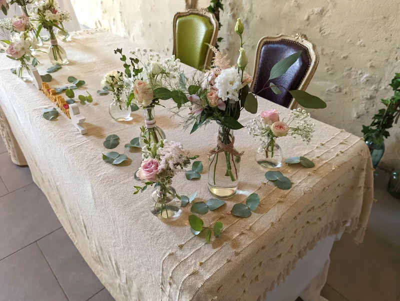 Countryside-inspired head table decoration with roses, eustoma, astilbe and gypsophila in an assortment of small vases.