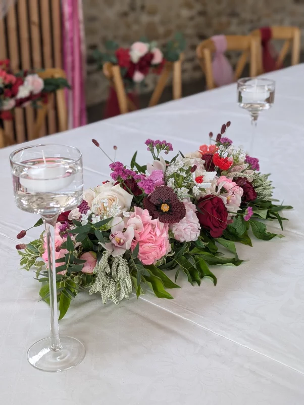 Décoration de table d'honneur romantique organique avec roses, pivoines et œillets pour mariage.